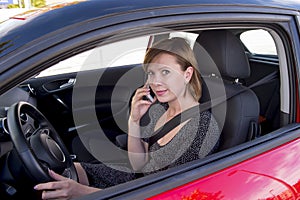 Woman talking happy on mobile phone while holding car steering wheel driving distracted