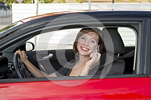 Woman talking happy on mobile phone while holding car steering wheel driving distracted