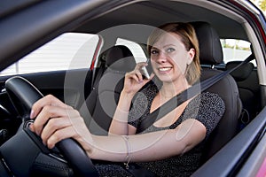 Woman talking happy on mobile phone while holding car steering wheel driving distracted