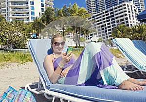 Woman talking on her cell phone while lounging on the beach