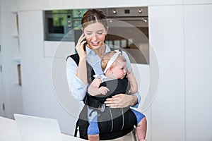 Woman talking on mobile phone while carrying baby girl