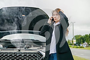 a woman is talking on a mobile phone next to a broken car. Calls technical assistance on the road