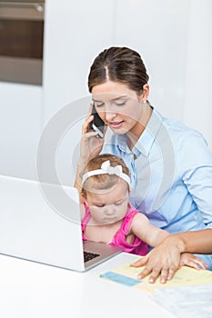 Woman talking on mobile phone sitting with baby girl