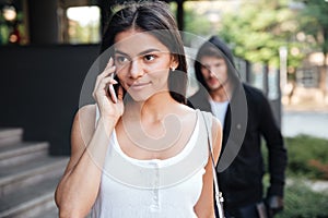 Woman talking on mobile phone and stalked by man criminal