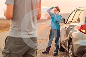 Woman talking on mobile phone by the stopped car