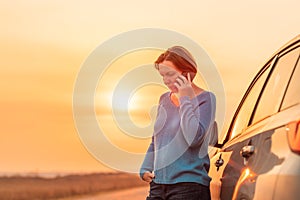 Woman talking on mobile phone by the stopped car