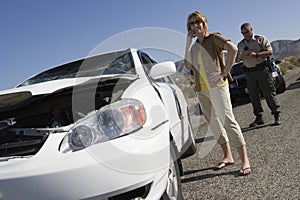 Woman Talking On Mobile Phone With Traffic Cop Writing Ticket On Street