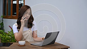 Woman talking on mobile phone and using computer laptop at outdoor.