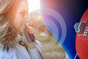 Woman talking by payphone at spring sunny day