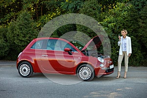 Woman talking phone asking for help beside her breakdown car in road