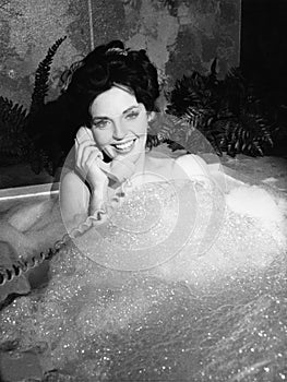 Woman talking on phone in bubble bath