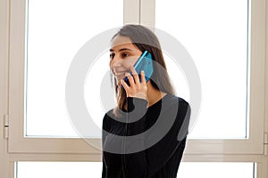Woman talking on the phone in front of a window.