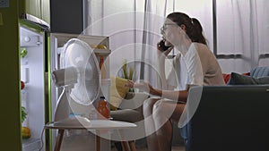 Woman talking on the phone at home and cooling in front of the fridge
