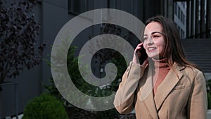 Woman talking phone outside in american style Business Center on the background