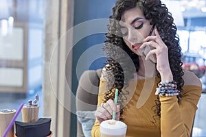 Woman talking on the phone stirring coffee