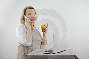 woman talking on phone is upset and displeased in hands she has apple dietetics proper nutrition menu recipes in front