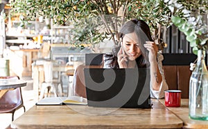 Woman talking on the phone while working with a laptop in a coffee shop