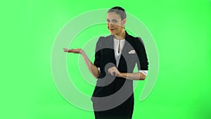 Woman talking and pointing side hand for something, copy space. Green screen