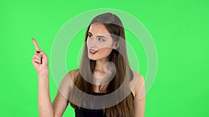 Woman talking and pointing side hand for something, copy space. Green screen