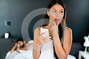 Woman talking privately on cellphone while her husband sleeping on bed photo