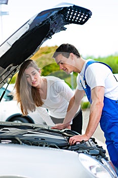 Woman talking to car mechanic in repair shop