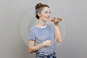 Woman talking to cell phone using virtual assistant, digital speaker application.