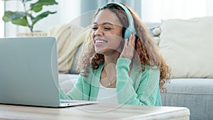Woman talking on video call using laptop and headphones while waving hello to friends online. Student communicating with