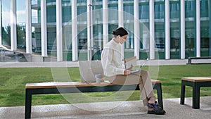 Woman talking video chat laptop sitting bench outdoors. Girl conducting webinar.