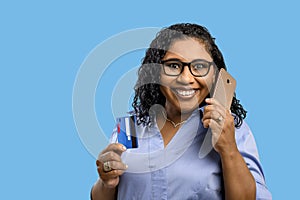 Woman talks on cellphone while holding credit card in other hand, shopping online, payment app payment