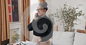 A woman talks on phone while staring into screen of laptop that sits on cardboard