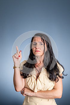 a woman in a tan shirt is holding her index up