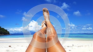 Woman tanned skin legs on the beach.