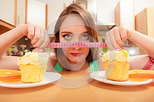 Woman with tape measure and cake. Diet dilemma.