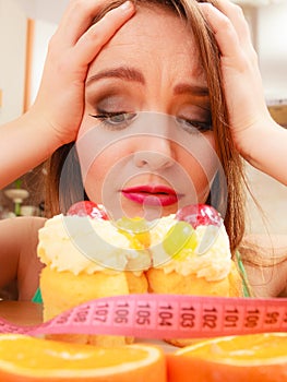 Woman with tape measure and cake. Diet dilemma