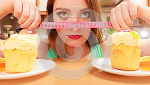 Woman with tape measure and cake. Diet dilemma.