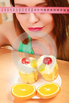 Woman with tape measure and cake. Diet dilemma.