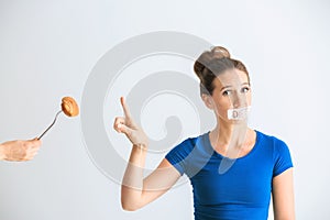 Woman with taped mouth refusing to eat unhealthy food on white background. Diet concept