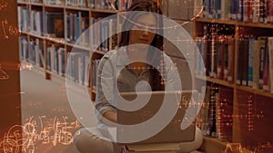 Woman taping in her laptop in the libary surronded by mathematics symbols