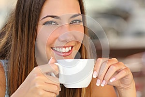 Woman tasting a coffee from a cup in a restaurant terrace