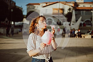 woman tasting cotton candy in a park at sunset. Travel and tourism concept.