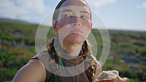 Woman tasting delicious bread on green hill closeup. Countryside girl smell loaf