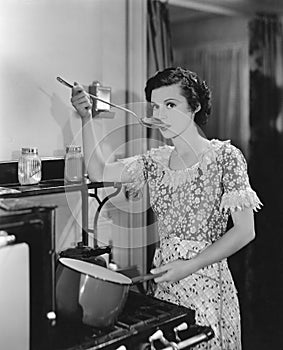 Woman tasting food cooking on stove