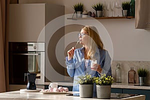 Woman tasting yogurt in sunlit kitchen