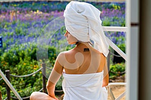 A woman with a tatoo in a bath towel is sitting on a lounge
