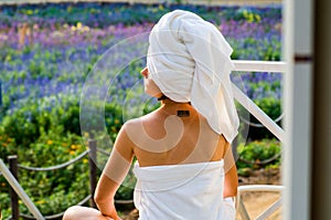 A woman with a tatoo in a bath towel is sitting on a lounge