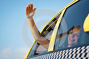 Woman in taxi waving hand out of car window