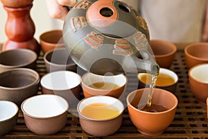 Woman Tea Master Hostess Pouring Tea into Cup from Pot at Ceremony. Chinese Japanese Set on Bamboo Wooden Tray. Freshly Brewed