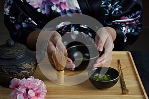 Woman tea master in kimono performs tea ceremony. Matcha green tea powder with a bamboo whisk and scoop