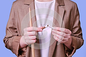 Woman teacher holding broken cigarette on studio blue background, close-up