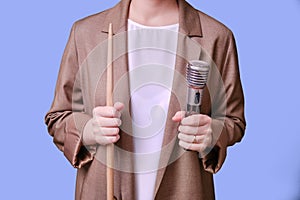 Woman teacher holding microphone in hand on studio blue background, copy space